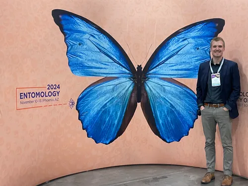 Standing in front of the Entomology 2024 sign