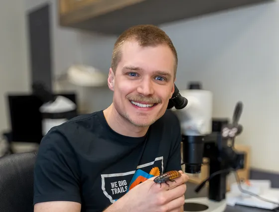 Jackson Strand at a microscope holding a sawfly